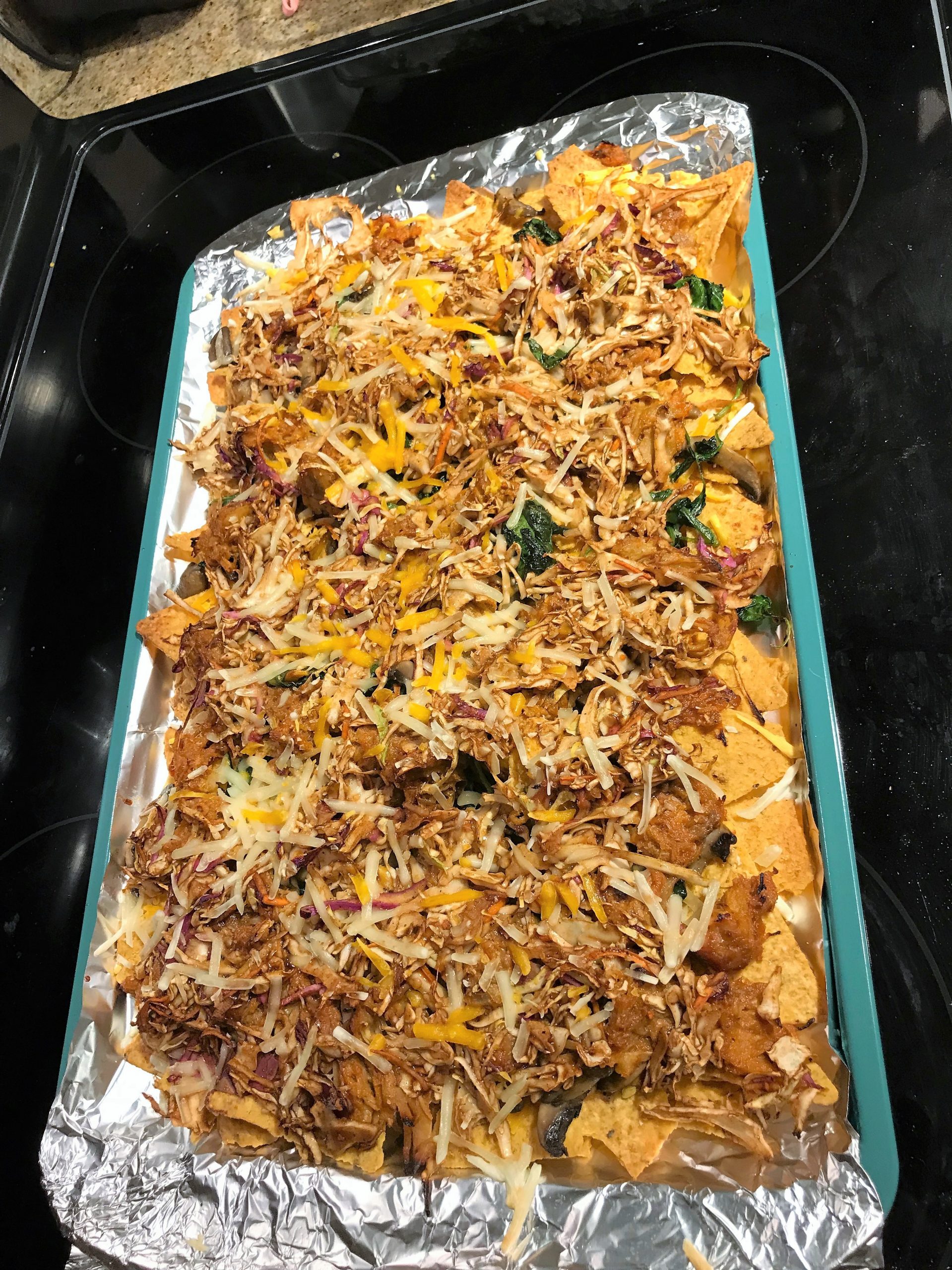 Putting the best nachos in the oven with all the toppings, taken by Allspice Photography, LLC.