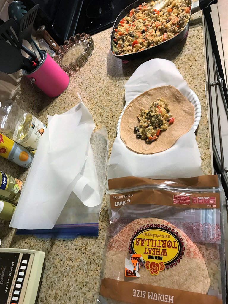 Assembly line process of stuffing the tortillas and wrapping them with parchment paper. Taken by Allspice Photography, LLC.